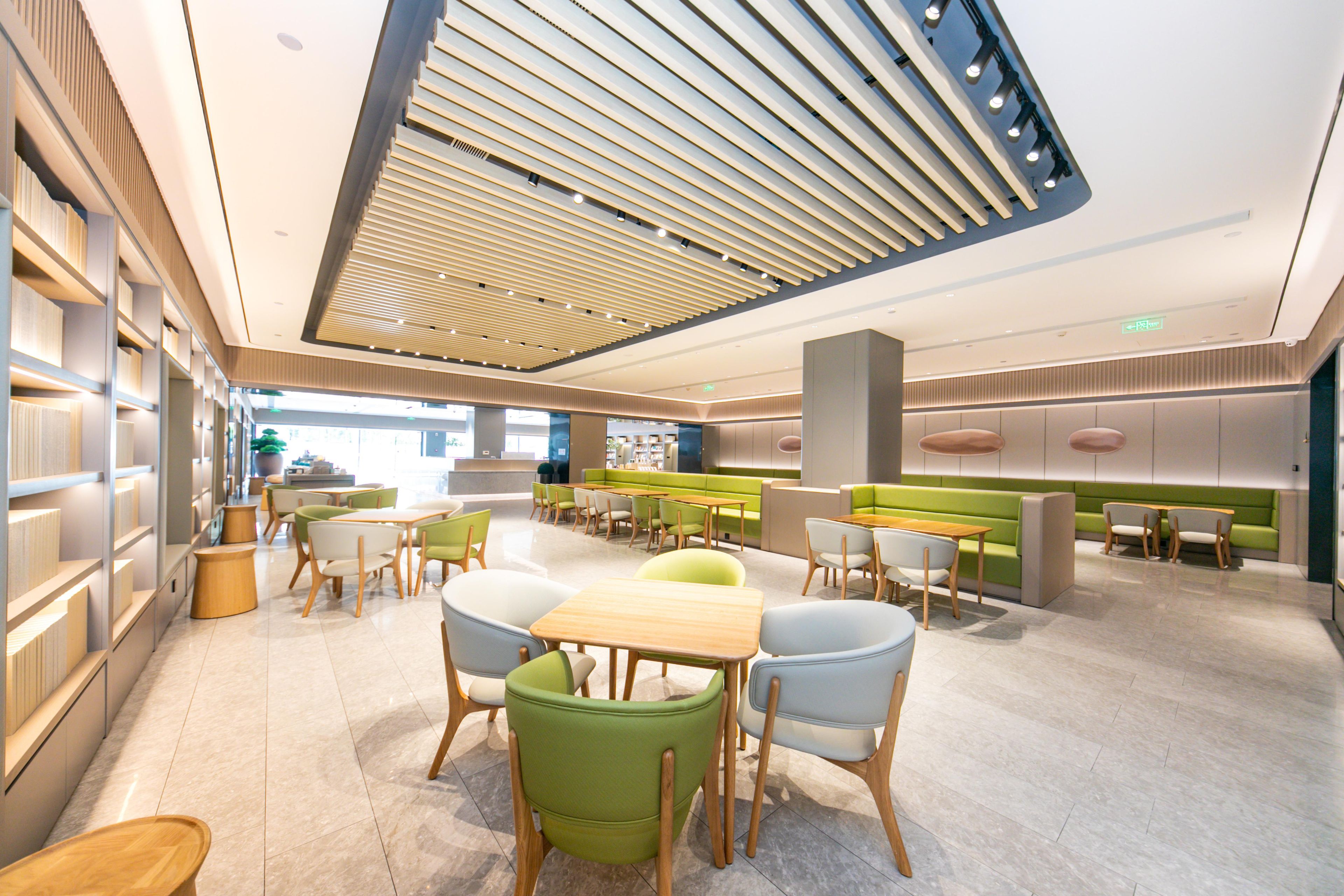 Un interior moderno con una zona de estar central, techo alto con diseño de listones y distribución luminosa y abierta.