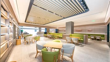 A modern interior with a central seating area, a high ceiling with slatted design, and a bright, open layout.