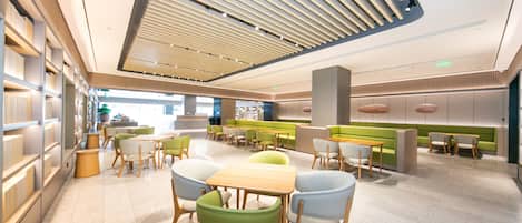 Un interior moderno con una zona de estar central, techo alto con diseño de listones y distribución luminosa y abierta.