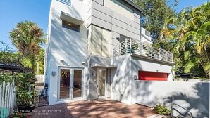 Una casa moderna de dos pisos con garaje, ventanas amplias y un balcón.