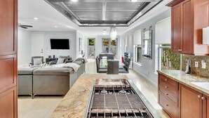 Una cocina moderna con una isla central, campana extractora de acero inoxidable y armarios de madera.