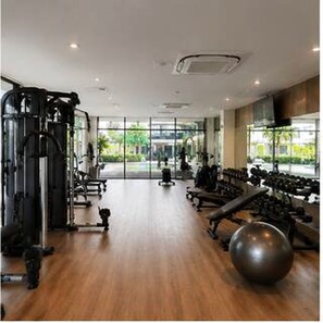 A gym with exercise equipment, a large window, and a wooden floor.