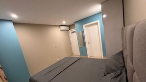 Een slaapkamer met een bed, een garderobe, een spiegel en een airconditioning.
