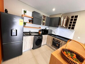 A modern kitchen with a built-in washing machine, a refrigerator, and a microwave.