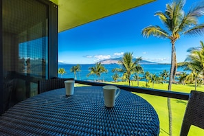 Relax on the balcony with a serene view of the tropical landscape, featuring a calm sea and distant mountains.