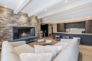 A modern living room with a stone fireplace, a sofa, and a coffee table. - Village Center C2J - 2 Bedroom Residence (vail)