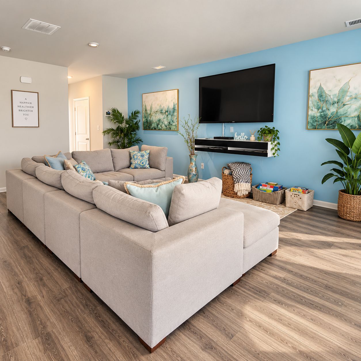 A modern living room with a sectional sofa, a flat-screen TV mounted on the wall, and decorative plants.