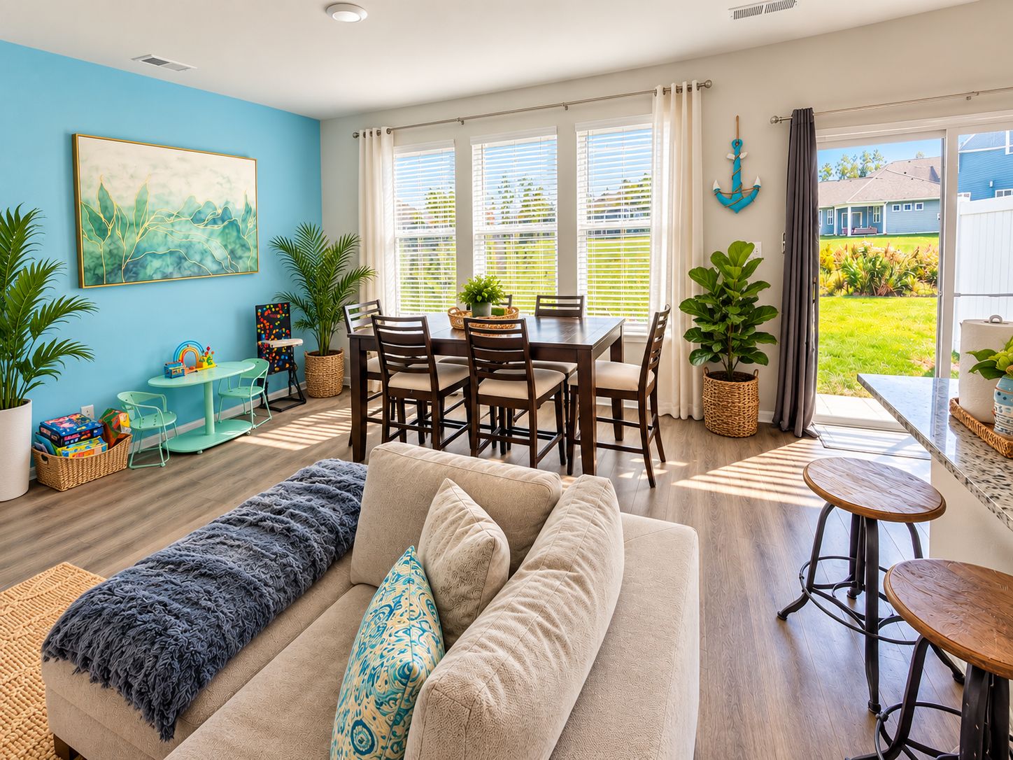 A living room with a sofa, a dining table with chairs, and a kitchen area with a bar stool.