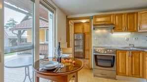 A kitchen with wooden cabinets, stainless steel appliances, and a dining area with a glass table and chairs.