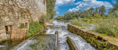 A stone building with a wooden staircase leading down to a river.