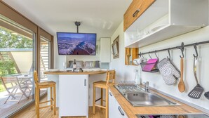A modern kitchen with a wooden countertop, a built-in sink, and a dining area with wooden chairs.