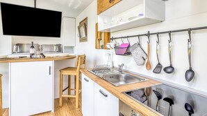A compact kitchen with a wooden countertop, a built-in sink, and a wall-mounted TV.