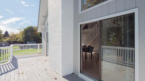 Ein modernes Haus mit einer Holzdiele, einer Glastür zum Aufschieben und einem weißen Zaun.