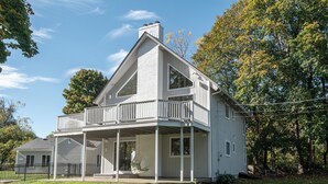 Ein zweistöckiges Haus mit Balkon, einer Veranda und einem Schornstein.