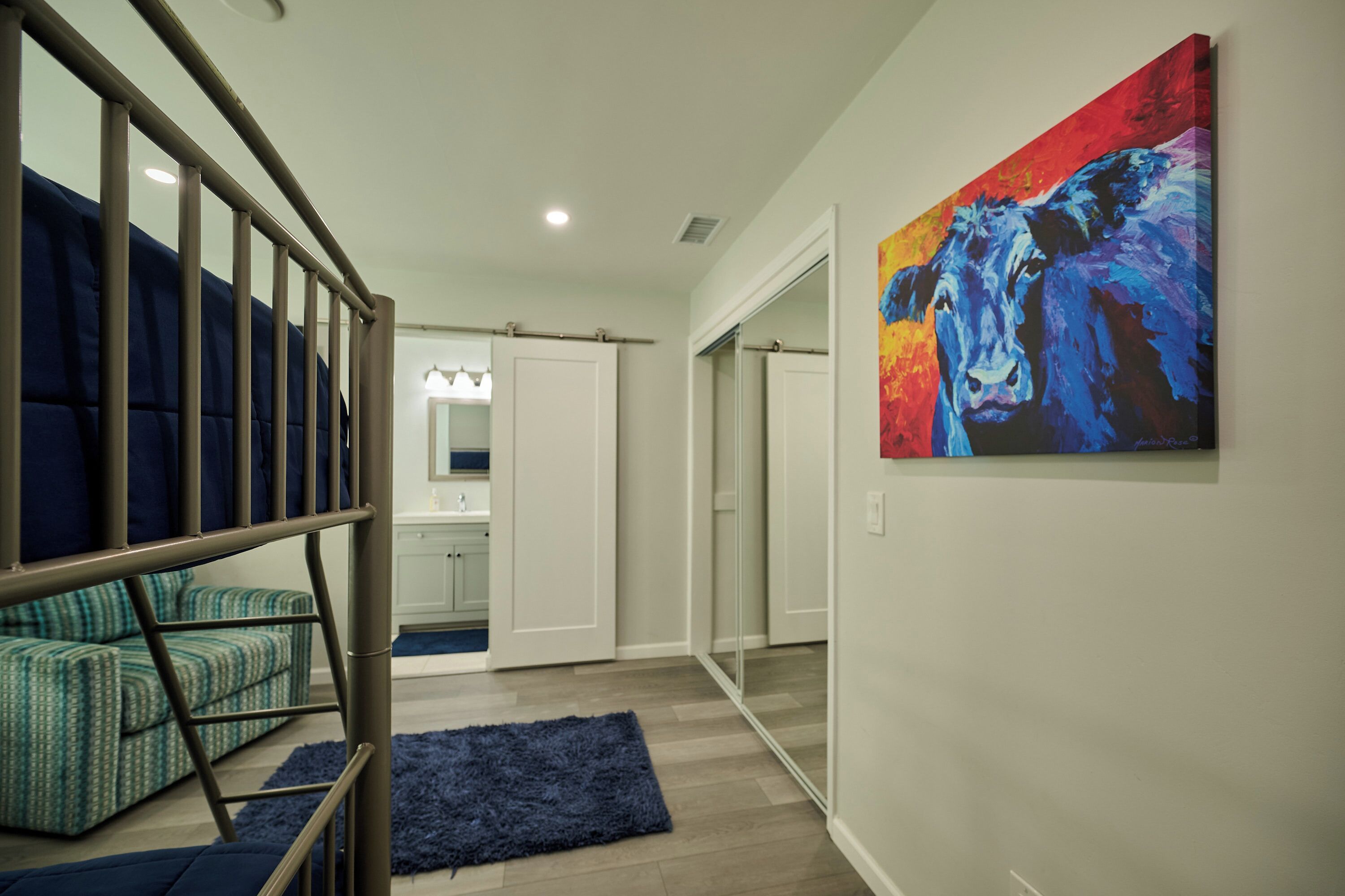 A modern interior with a staircase, a blue rug, and a colorful painting on the wall.