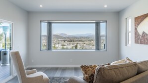 Una sala de estar moderna con un ventanal que ofrece vistas a la ciudad, un sofá cómodo y una silla.