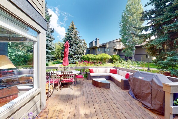 Relax and unwind in this serene outdoor space, featuring a comfortable seating area, barbecue grill, and lush greenery.