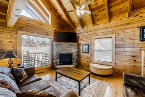 Cozy living room with a stone fireplace, leather sofa, and vaulted ceiling.