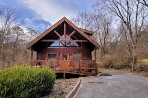 Escape to a secluded cabin surrounded by nature, offering a retreat with a wooden deck and paved area.
