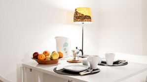 A clean, white dining area with a table set for breakfast, including fruits, a pitcher, and cups. - RESIDENZA SANSONI charming and easy (Roma)