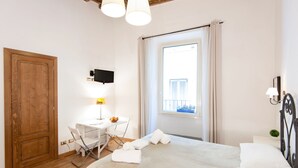 A bedroom with a bed, a desk, a chair, a TV, and a window with curtains. - RESIDENZA SANSONI charming and easy (Roma)