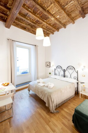 A bedroom with a wooden ceiling, a bed with white linens, a bedside table with a lamp, and a window with curtains. - RESIDENZA SANSONI charming and easy (Roma)