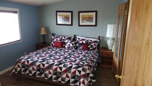 A bedroom with a bed, two nightstands, a window, and two framed pictures on the wall.