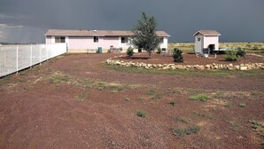 A two-story building with a fenced yard, a small tree, and a gravel driveway.