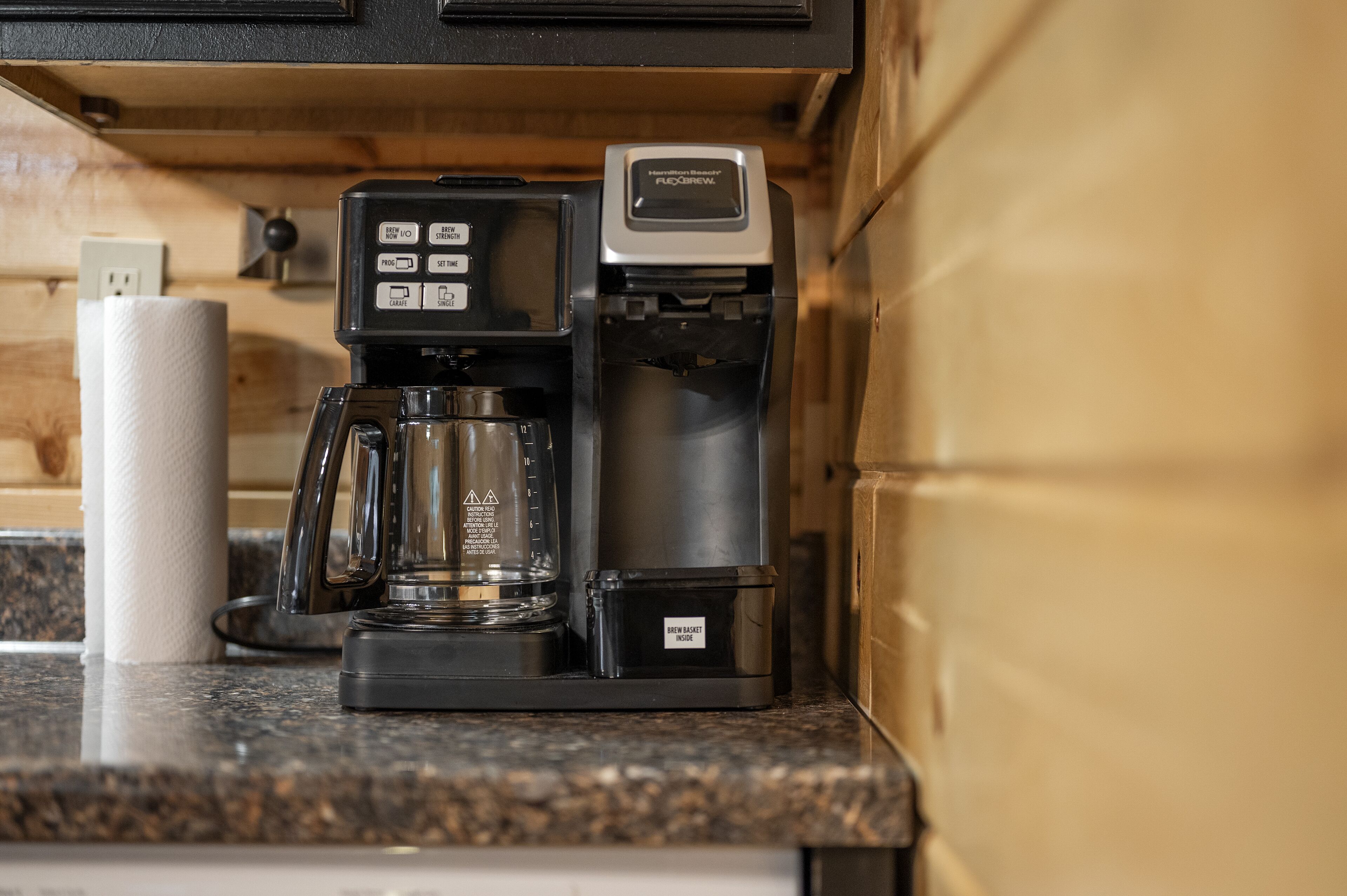 En kaffebryggare står på en bänkskiva av granit, och bredvid den ligger en rulle hushållspapper.