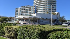 A modern multi-story hotel with a curved facade, multiple balconies, and a central atrium.