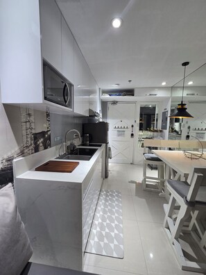 Une cuisine moderne dotée d’un îlot central, d’appareils électroménagers en acier inoxydable et d’un coin repas avec des meubles blancs.