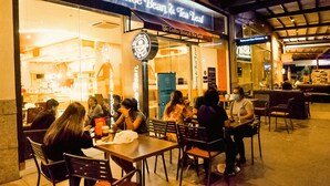 A coffee shop with tables and chairs outside, a sign above the entrance, and a person standing near the entrance. - 1 BR- INSPIRIA RESIDENCE CONDOMINIUM, Abreeza Mall,  Bajada, Davao City. (Davao City)