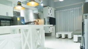 A modern kitchen with white cabinetry, a central island, pendant lighting, and a view of a cityscape through a window. - 1 BR- INSPIRIA RESIDENCE CONDOMINIUM, Abreeza Mall,  Bajada, Davao City. (Davao City)