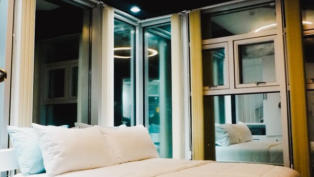 A modern bedroom with a bed, large windows, and a circular ceiling light. - 1 BR- INSPIRIA RESIDENCE CONDOMINIUM, Abreeza Mall,  Bajada, Davao City. (Davao City)