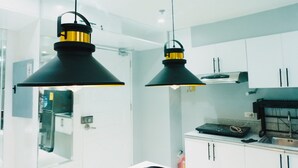 A modern kitchen with white cabinets, a black countertop, and two hanging pendant lights. - 1 BR- INSPIRIA RESIDENCE CONDOMINIUM, Abreeza Mall,  Bajada, Davao City. (Davao City)