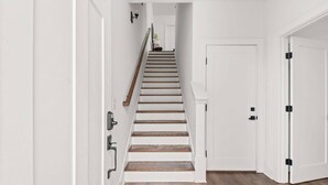 A staircase with wooden steps and white walls, leading to a door at the top. - Rosedale ~ Huge New Condo ~ 3BR + Bonus ~ 3 Miles to Broadway ~ Near GEODIS Park (Nashville)
