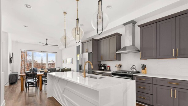 A modern kitchen with a large island, dark grey cabinets, and a white countertop. - Rosedale ~ Huge New Condo ~ 3BR + Bonus ~ 3 Miles to Broadway ~ Near GEODIS Park (Nashville)