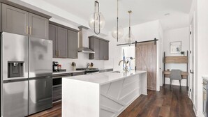 A modern kitchen with a large island, stainless steel appliances, and pendant lighting. - Rosedale ~ Huge New Condo ~ 3BR + Bonus ~ 3 Miles to Broadway ~ Near GEODIS Park (Nashville)
