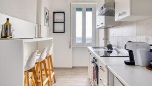 Ett modernt kök med vita skåp, en inbyggd ugn och en kaffemaskin.