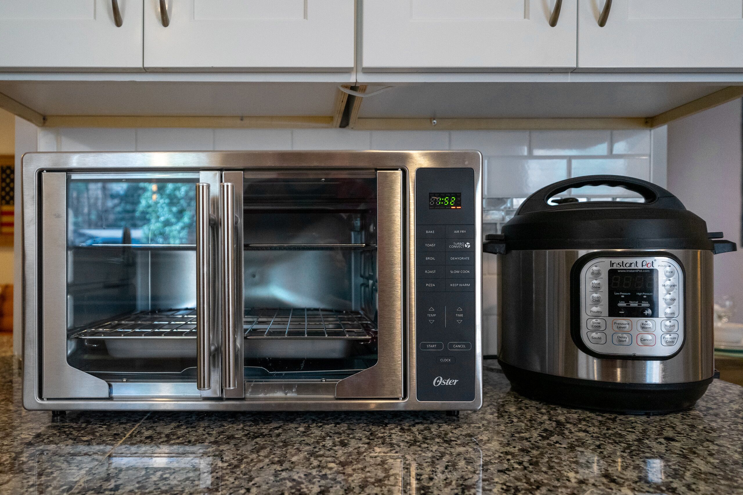 A stainless steel oven with a digital display and a black Instant Pot beside it.