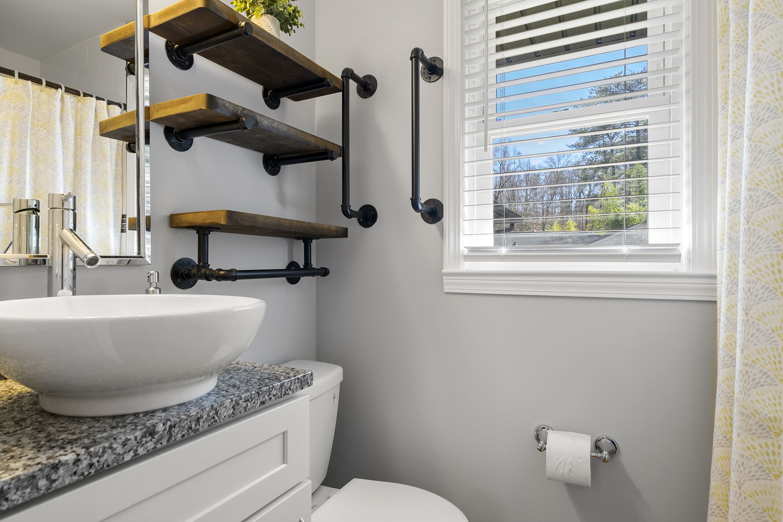 A bathroom with a white sink, a toilet, and a window with blinds.