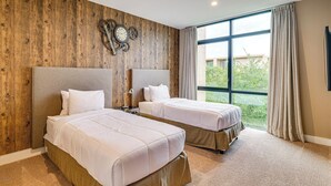 A hotel room with two beds, wooden paneling on the walls, a large window with curtains, and a clock on the wall. - Magic Villas Townhome ~ 5 Mi to Disney Parks! (Kissimmee)