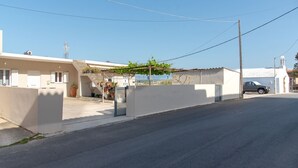 A quiet street with a row of white buildings, a parked car, and a clear blue sky. - Aria 1 - Vacation apartment in Crete, 100 m from the seaside (Kolimbári)