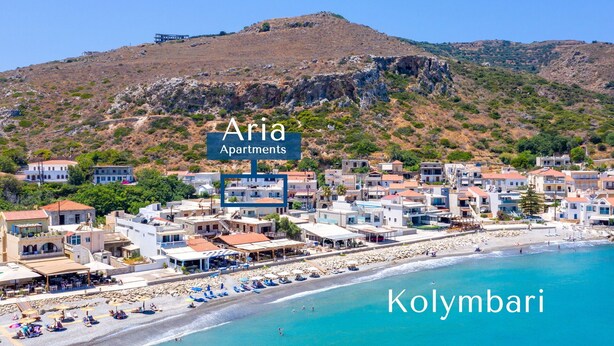 A coastal town with a beach, named Kolymbari, featuring a mix of residential buildings and a rocky hillside in the background. - Aria 1 - Vacation apartment in Crete, 100 m from the seaside (Kolimbári)
