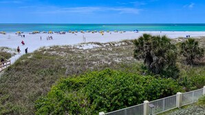 Ein Strand mit Menschen, Sonnenschirmen und blauem Himmel.