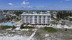 Ein mehrstöckiges Hotel mit Poolbereich, umgeben von Grünflächen und einem Strand.