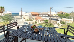 A balcony with a table set for tea, overlooking a residential area with houses and a view of the sea. - Aria 2 - Vacation apartment in Crete, 100 m from the seaside (Kolimbári)