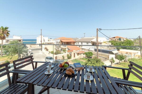 Ein Balkon mit gedecktem Tisch für Tee, mit Blick auf ein Wohngebiet, Häuser und das Meer.