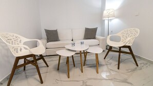 A modern living room with a sofa, two chairs, a coffee table, and a floor lamp. - Aria 3 - Vacation Apartment in Crete, 100 m from the seaside (Kolimbári)