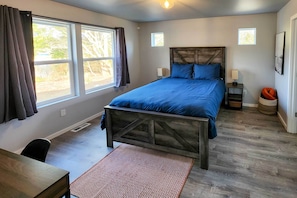 Un dormitorio con una cama grande, cabecera de madera, un escritorio y una ventana con cortinas.